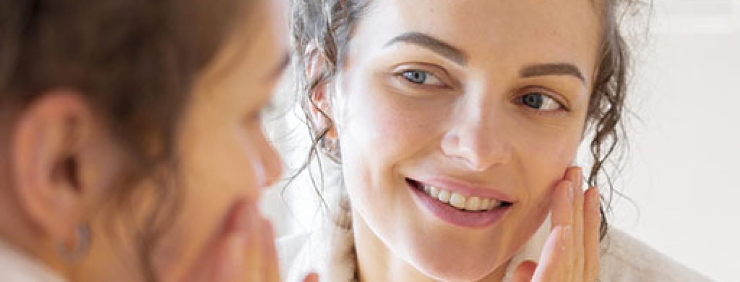 Mulher olhando seu rosto após tratametno de Acne